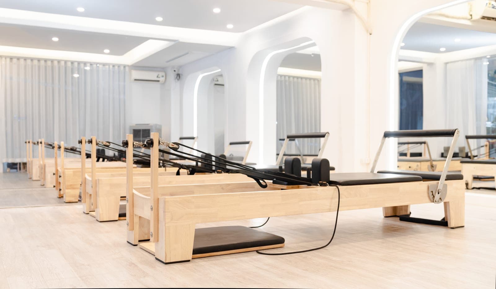 A minimal studio with wooden pilates reformers in daylight